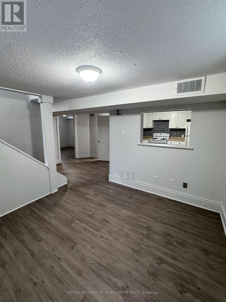 A room with a staircase and a window with a view of a kitchen.