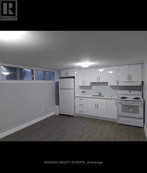 A kitchen with white appliances and cabinets in a real estate listing.