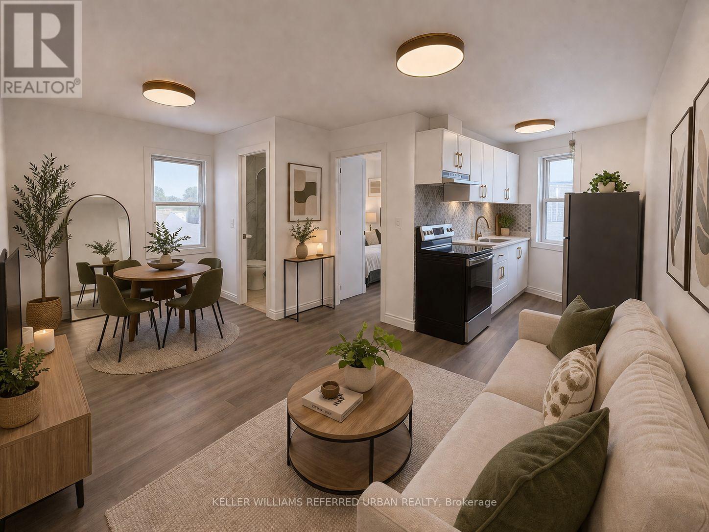 A well-lit, modern living room with a dining area and kitchen in the background.