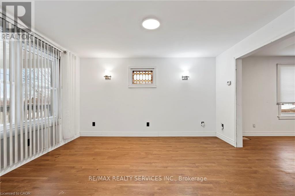 A room with wooden floors and white walls, with a window and a door visible.