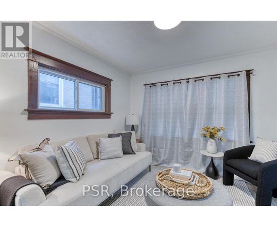 A living room with a sofa, a chair, and a table with a vase of flowers on it.