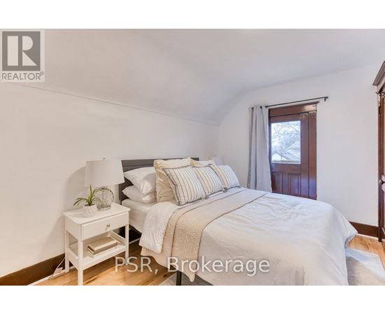 A bedroom with a bed, nightstand, and window.