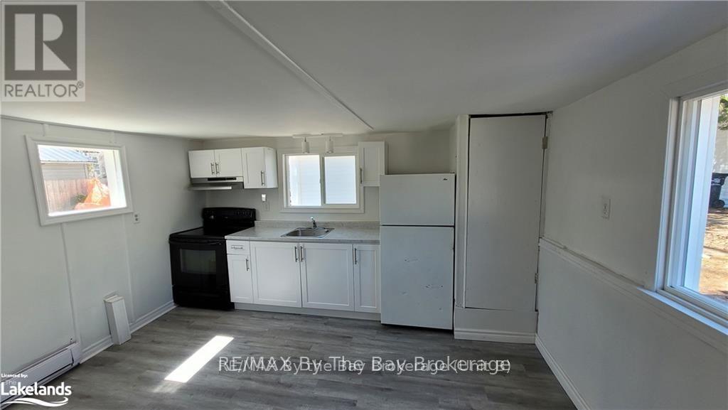 A kitchen area with white cabinets and a black refrigerator.
