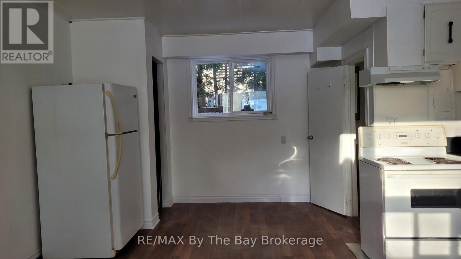 A kitchen with white appliances and a window.