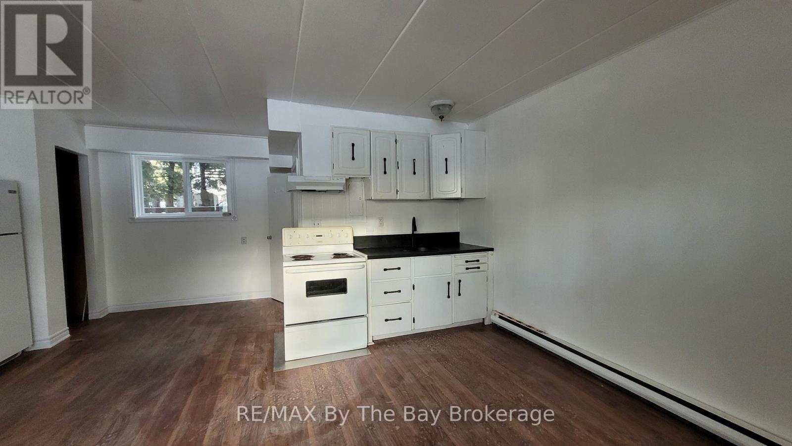 A kitchen with white cabinets and a wooden floor.