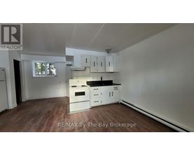 A kitchen with white cabinets and a wooden floor.