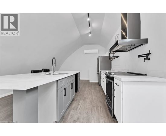 A modern kitchen with white cabinets and a stainless steel range hood.
