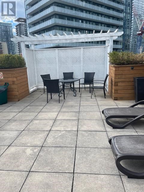 A patio with a white pergola and black chairs.