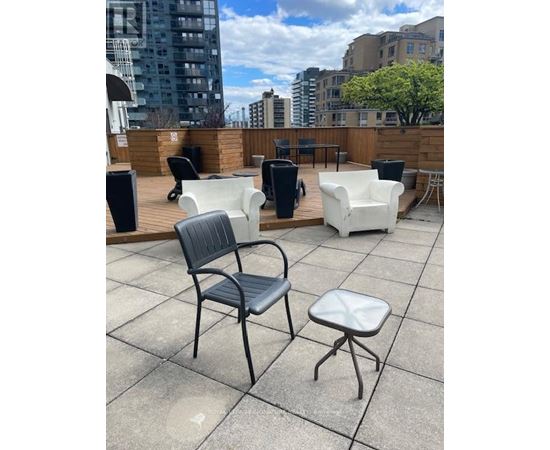A patio with a black chair, a white chair, and a white ottoman.