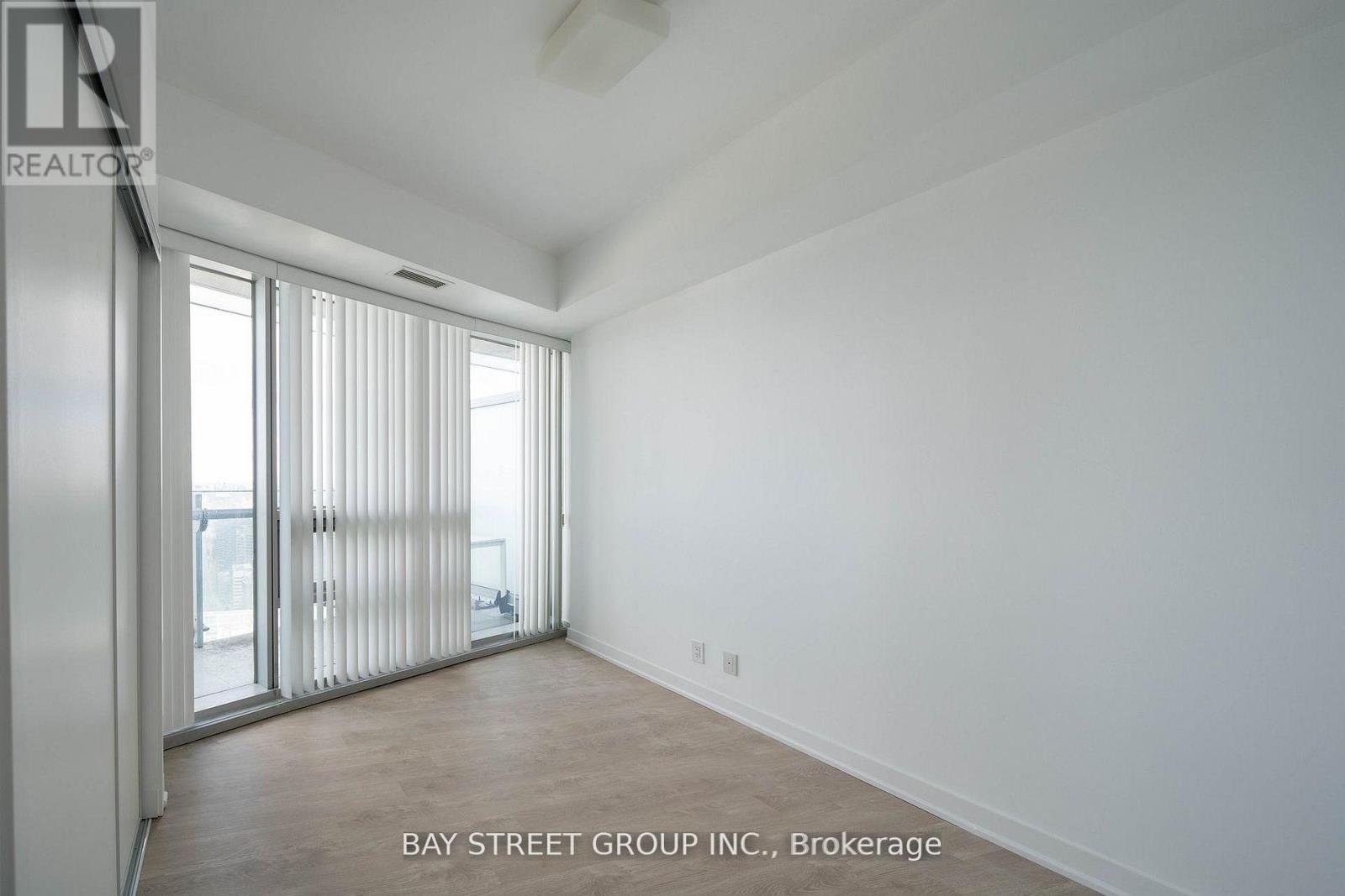 A spacious room with a sliding glass door leading to a balcony.