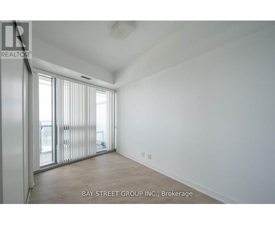 A spacious room with a sliding glass door leading to a balcony.