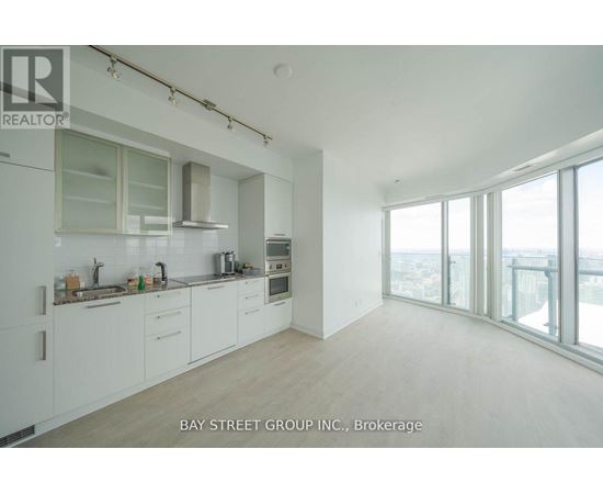A spacious kitchen with white cabinets and a view of the city.
