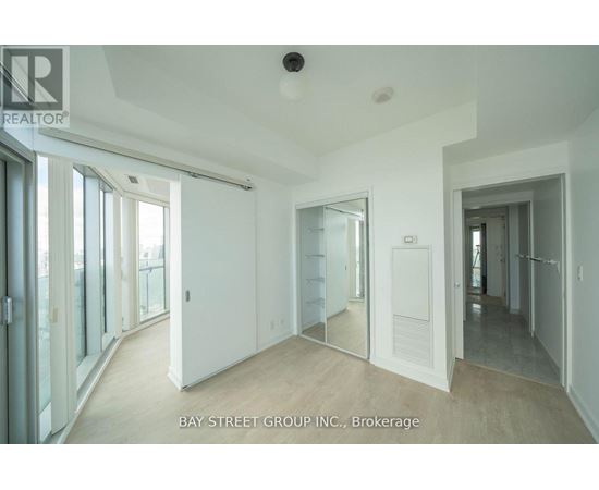 A spacious room with a sliding glass door leading to a balcony.
