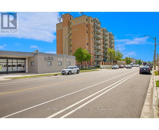 A street view with a car driving on the road and buildings on the side.