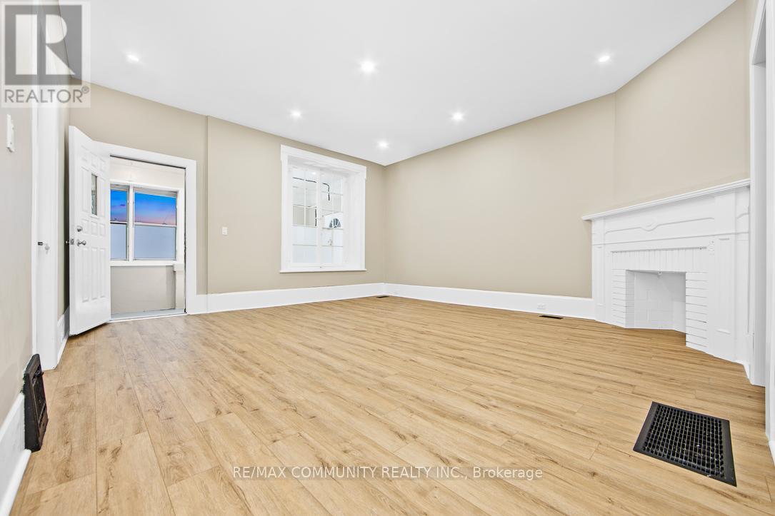 A spacious room with wooden flooring and a fireplace.