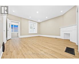 A spacious room with wooden flooring and a fireplace.