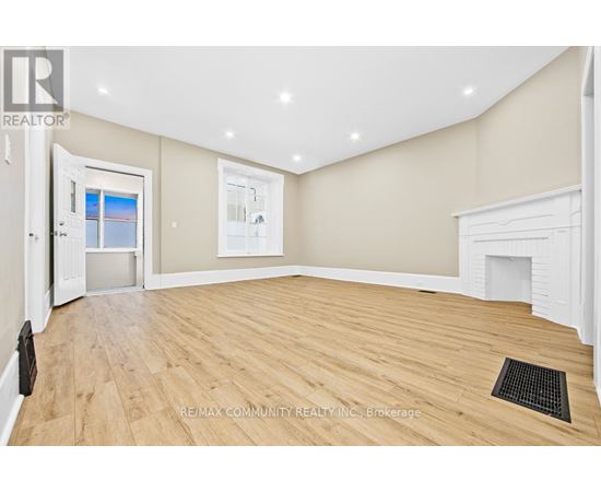 A spacious room with wooden flooring and a fireplace.