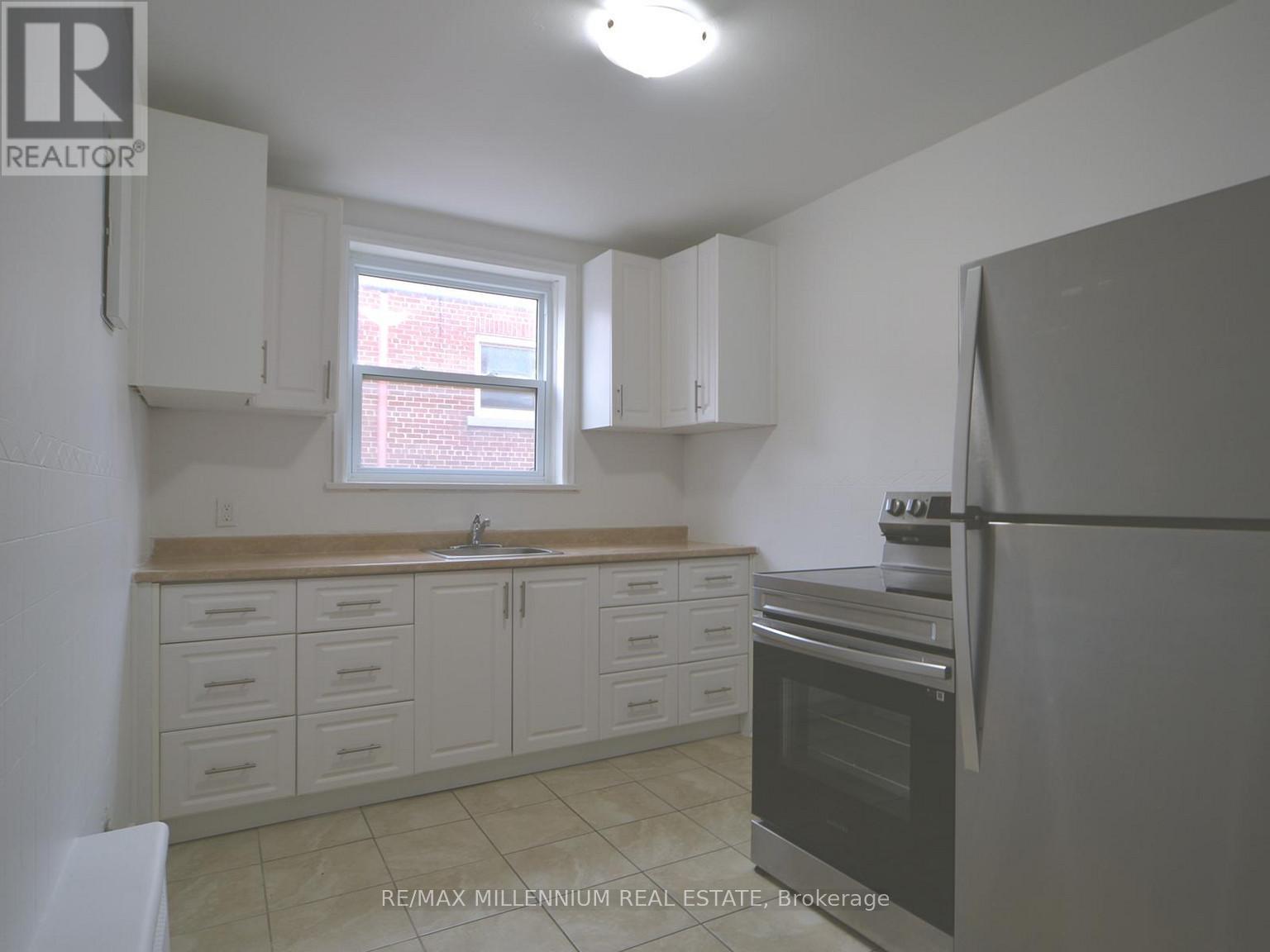 A kitchen with white cabinets and a black refrigerator.