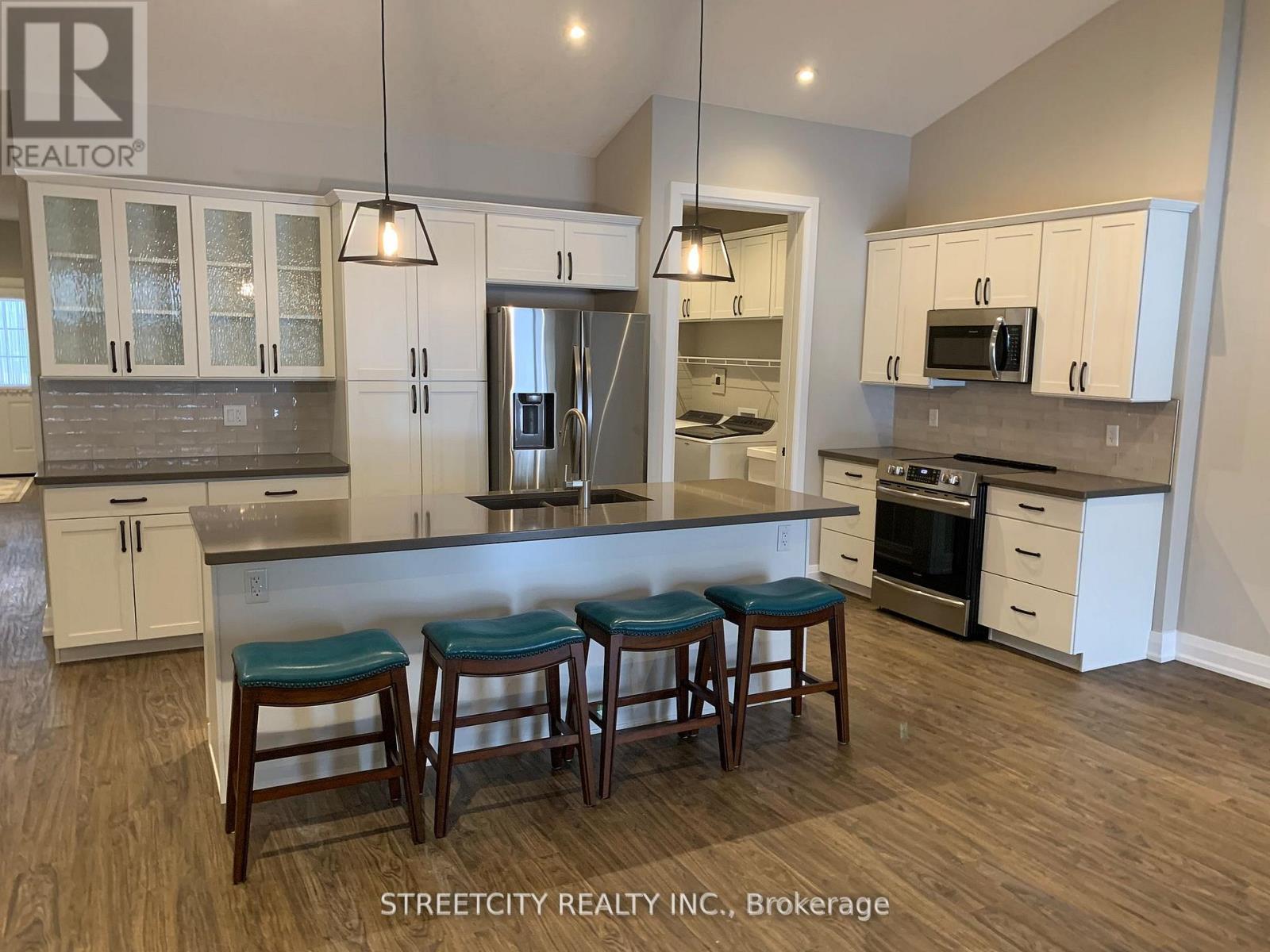 A kitchen with white cabinets and a bar area with stools.