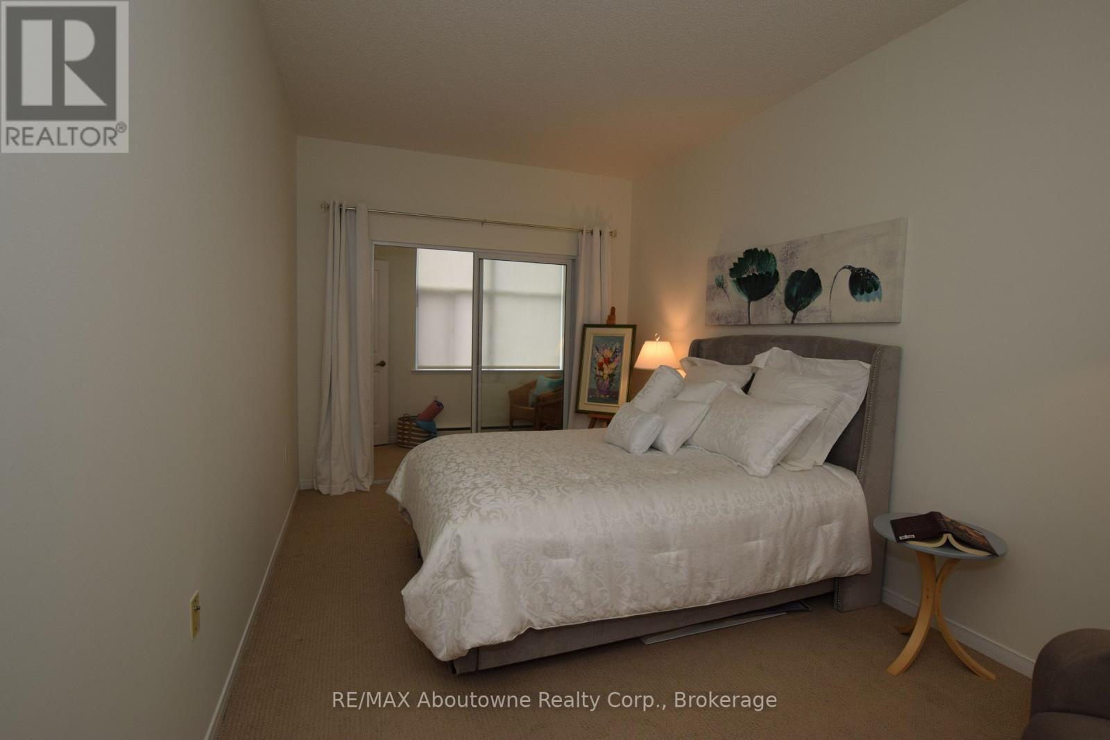 A bedroom with a bed, nightstand, and window.