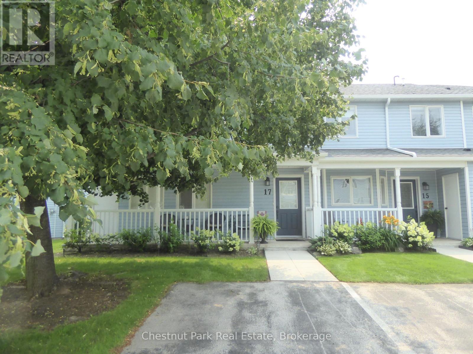 A blue house with a white fence and a tree in front.