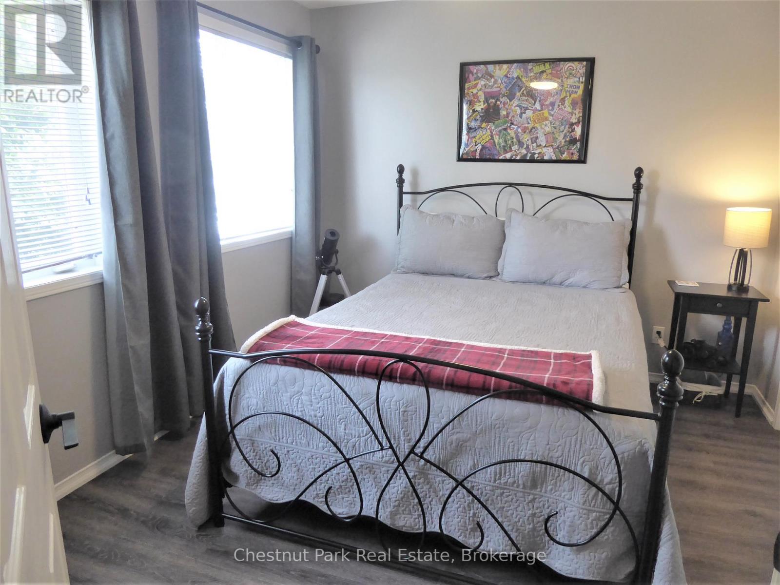 A bedroom with a bed, nightstand, and window.