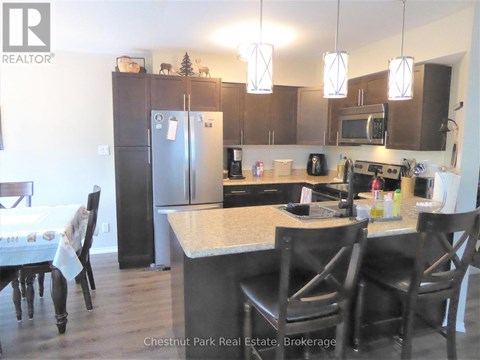 A kitchen with a table and chairs in front of it.