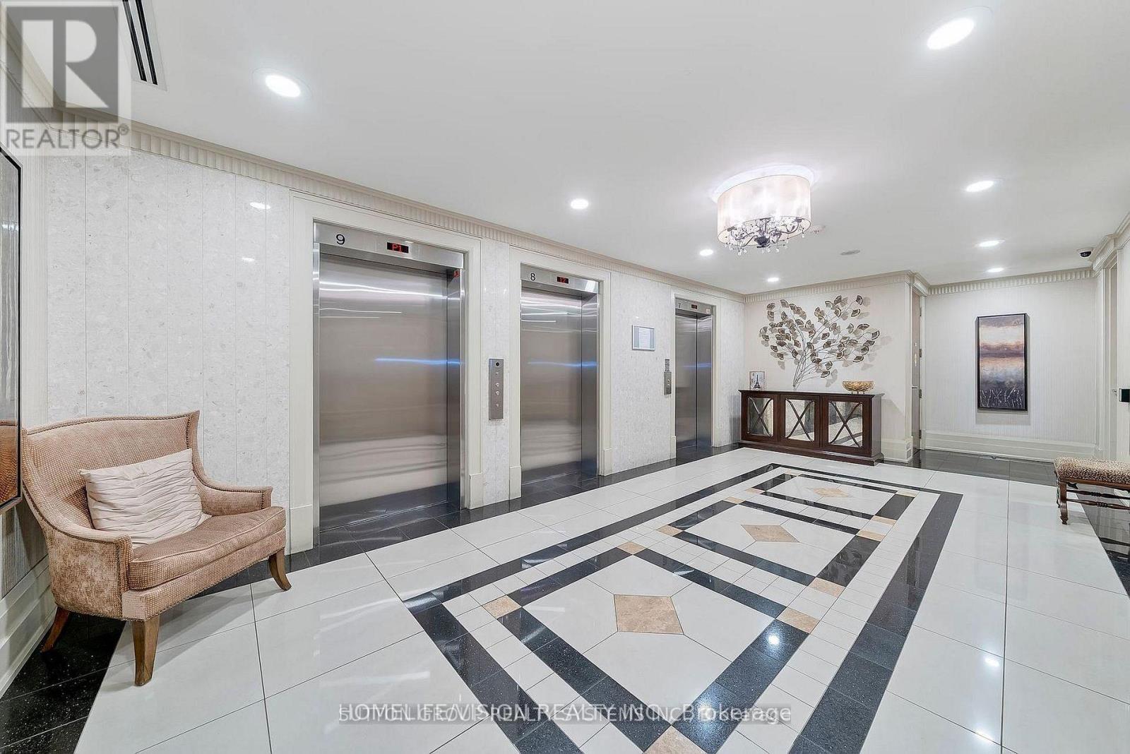 A spacious hallway with marble flooring and a chandelier.