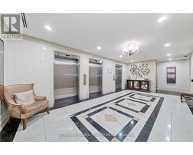 A spacious hallway with marble flooring and a chandelier.