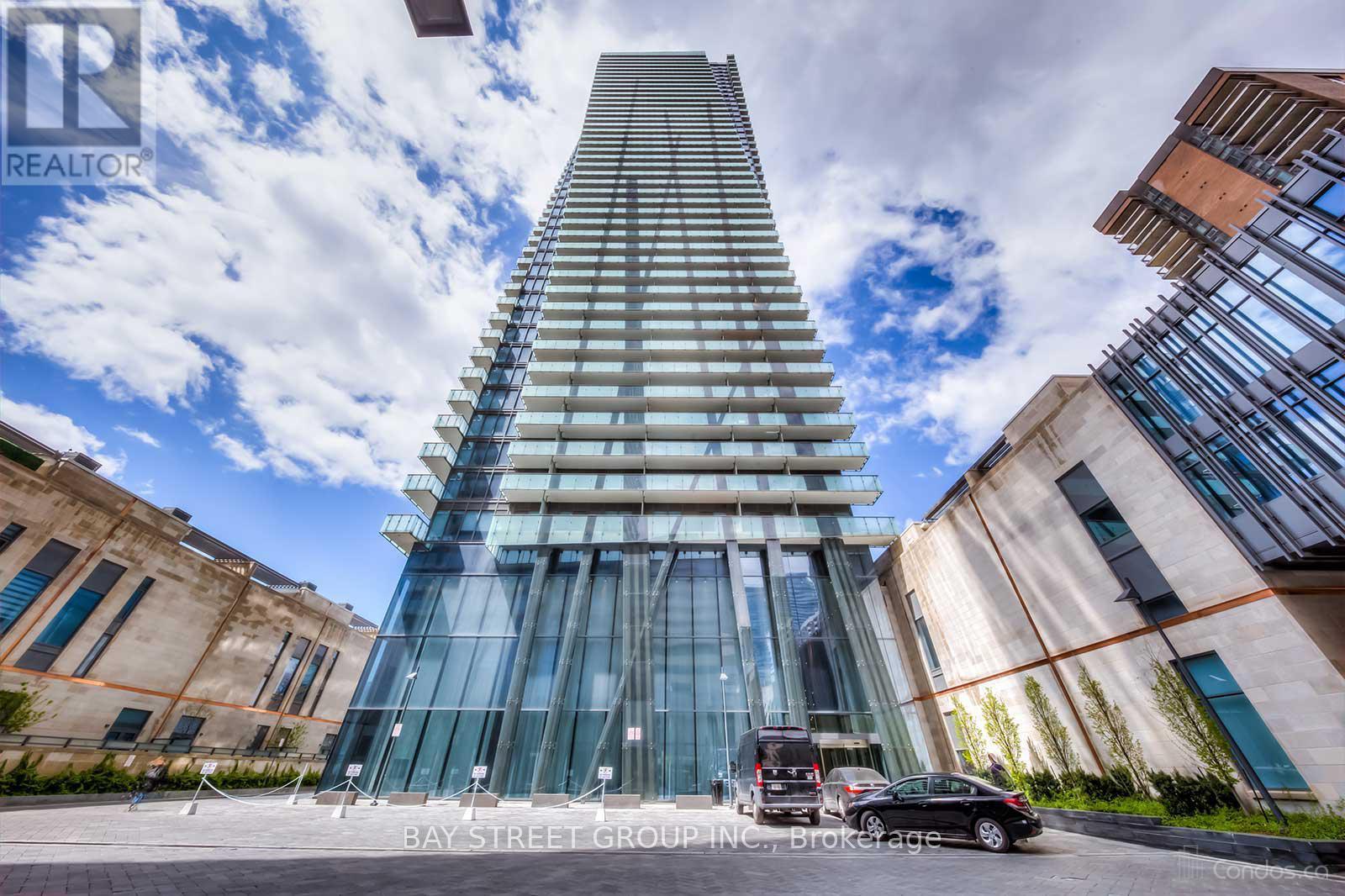 A modern glass building with a car parked in front.