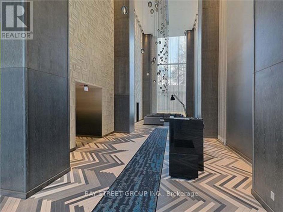 A hallway with a blue runner and a black trash can.