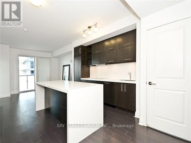 A modern kitchen with dark brown cabinets and white countertops.