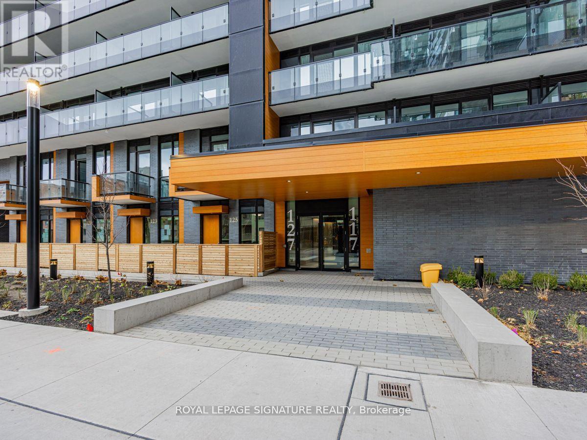 A modern building entrance with a glass door and a wooden overhang.