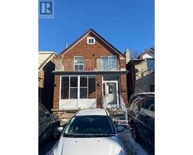 A white car is parked in front of a brick house.