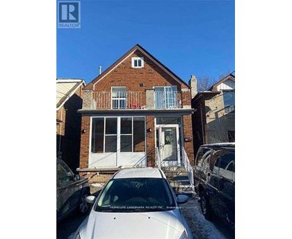 A white car is parked in front of a brick house.