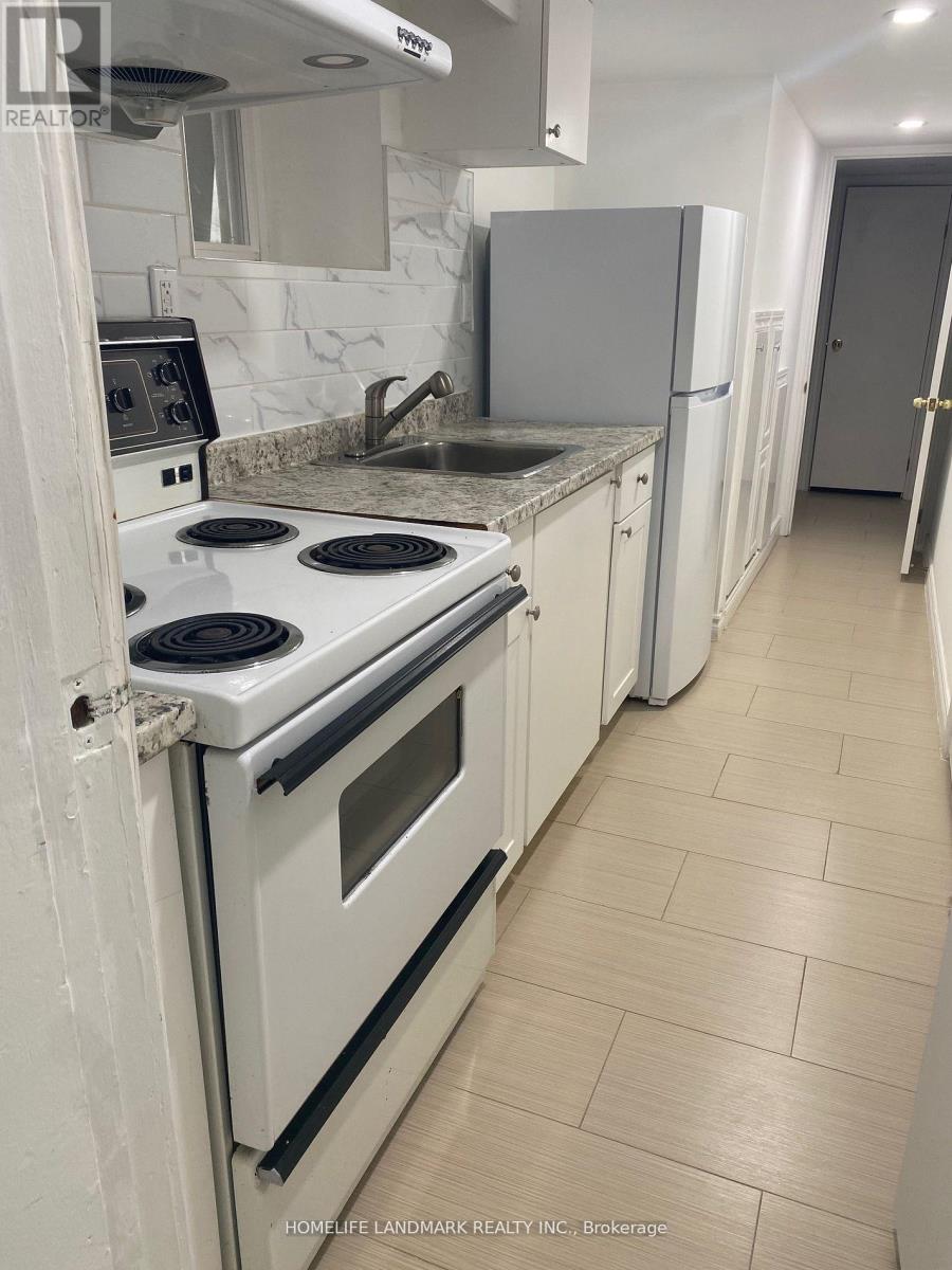 A kitchen with a white stove top oven and white cabinets.