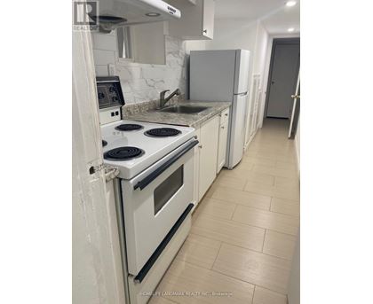 A kitchen with a white stove top oven and white cabinets.