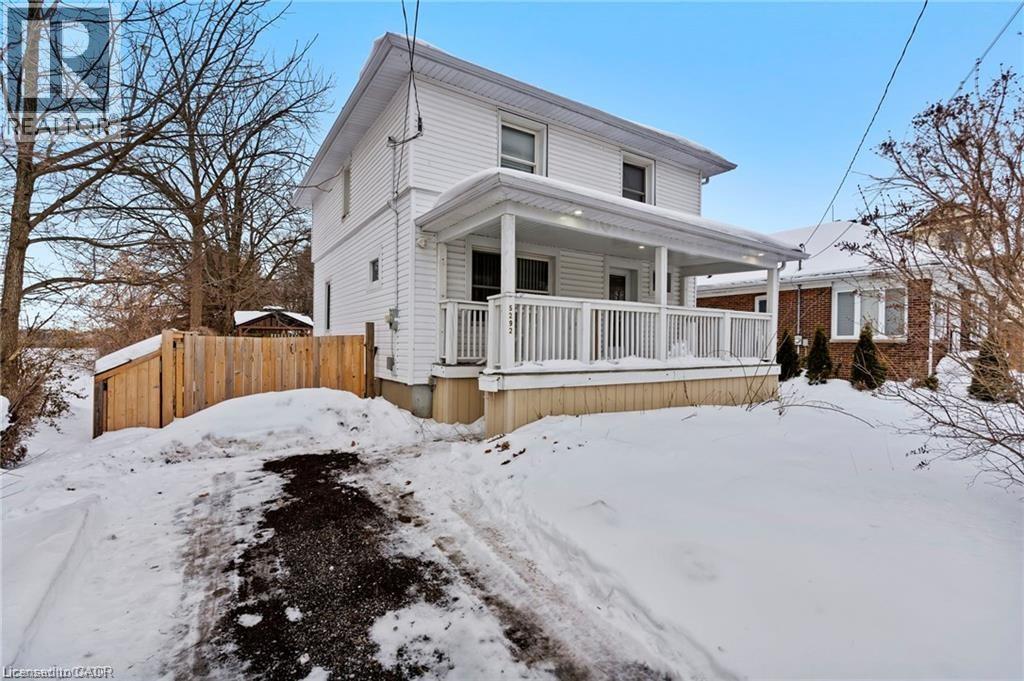 A white house with a wooden fence and snow on the ground.