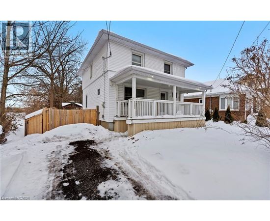 A white house with a wooden fence and snow on the ground.