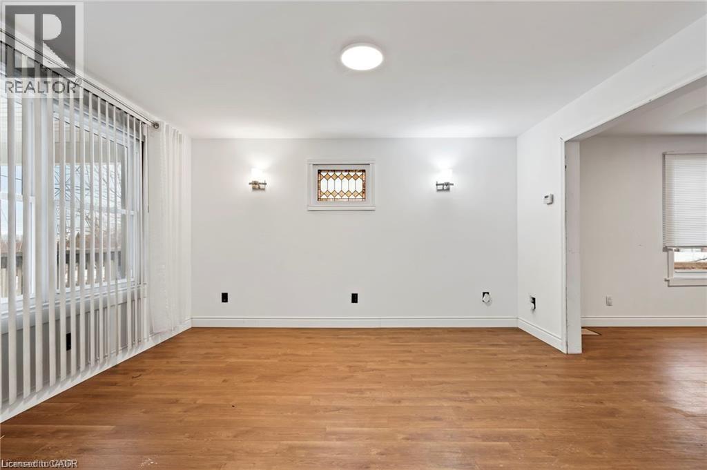 A room with wooden floors and white walls, with a window and a door visible.