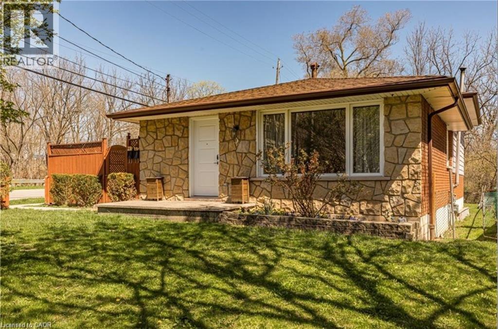A house with a brown roof and a white door is surrounded by a grassy lawn.