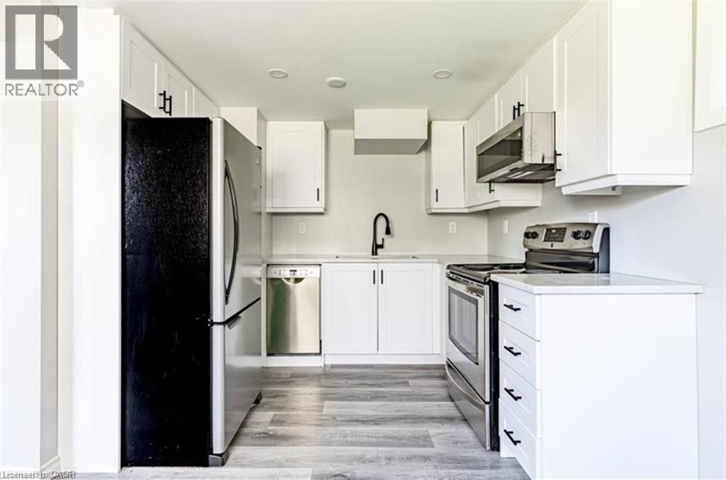 A white kitchen with a black fridge and stove top oven.
