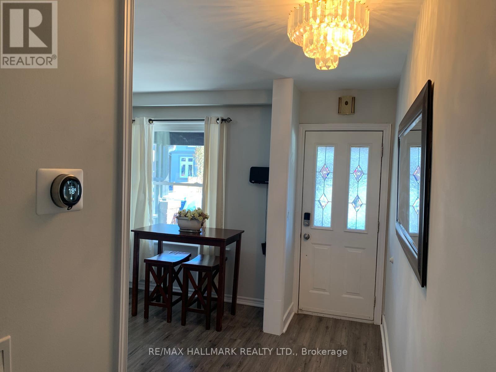 A hallway with a chandelier, a door, and a table with chairs.