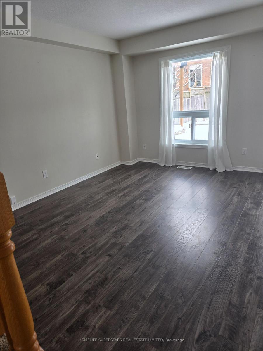A room with wooden flooring and a window with white curtains.