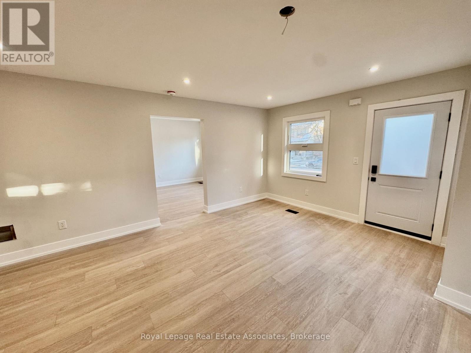 A spacious room with wooden flooring and white walls.