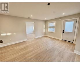 A spacious room with wooden flooring and white walls.