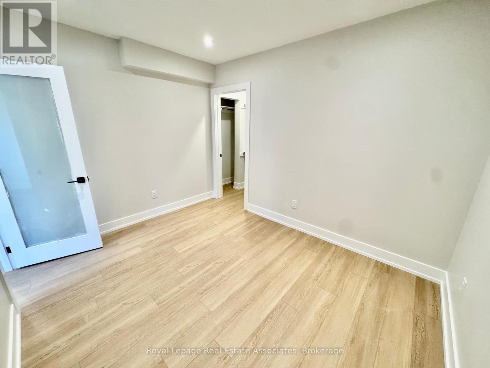 A room with wooden flooring and white walls, with a doorway leading to another room.