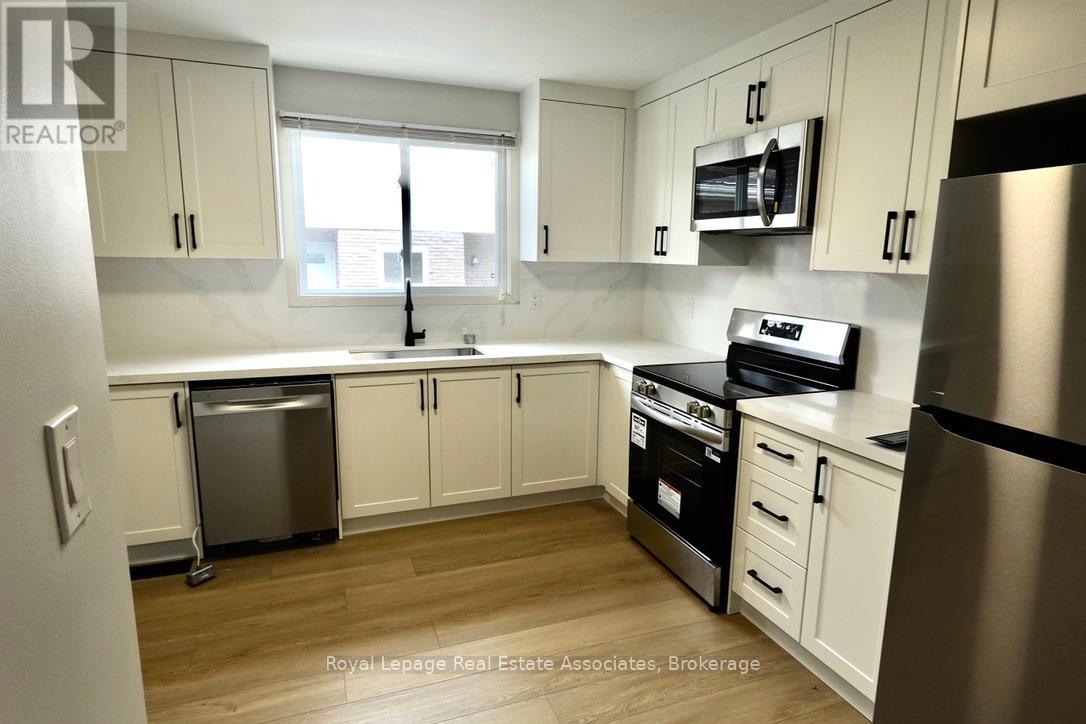 A kitchen with white cabinets and a stainless steel refrigerator.
