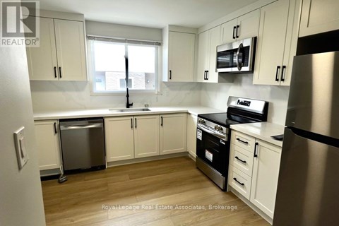 A kitchen with white cabinets and a stainless steel refrigerator.