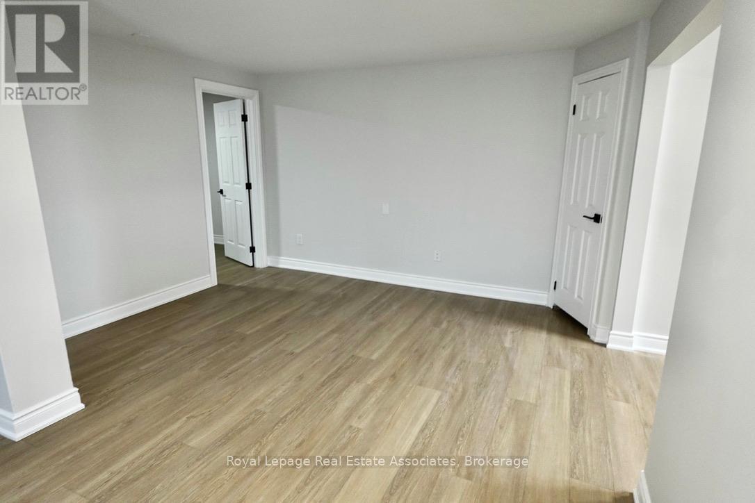 A room with wooden flooring and white walls, with a door on the left and a closet on the right.